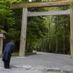 伊勢神宮の参拝前に鳥居の前で一礼する人物